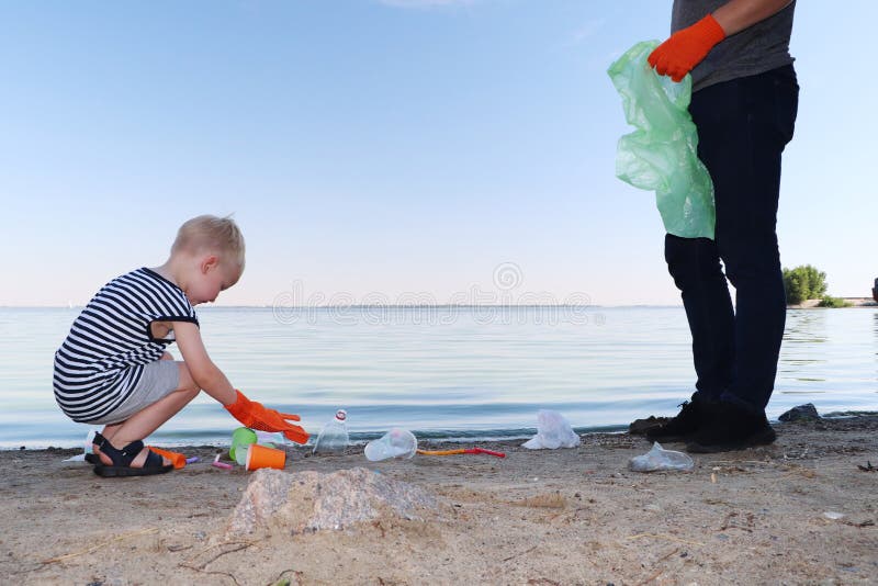 Een klein kind verzamelt afval op het strand Zijn papa richt zijn vinger waar te om huisvuil te werpen De ouders onderwijzen kind royalty-vrije stock afbeeldingen Een klein kind verzamelt afval op het strand Zijn papa richt zijn vinger waar te om huisvuil te werpen De ouders onderwijzen kind royalty-vrije stock afbeeldingen