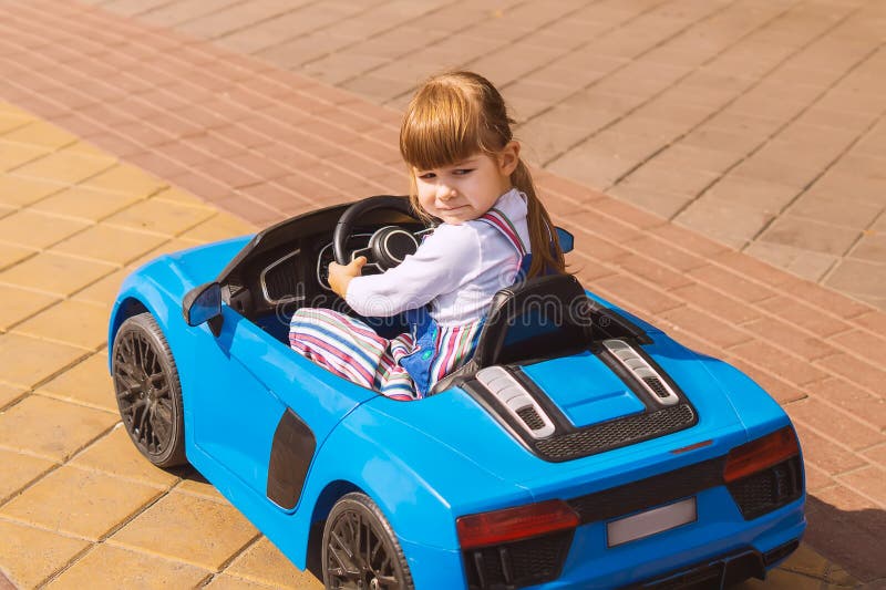 Een Klein Meisje Bestuurt Een Auto Die Op Batterijen Werkt in Een Een Gelukkig Kind Zit in Zijn Blauwe Speelgoedauto. De Stock Afbeelding - Image of familie, pret: 230168507