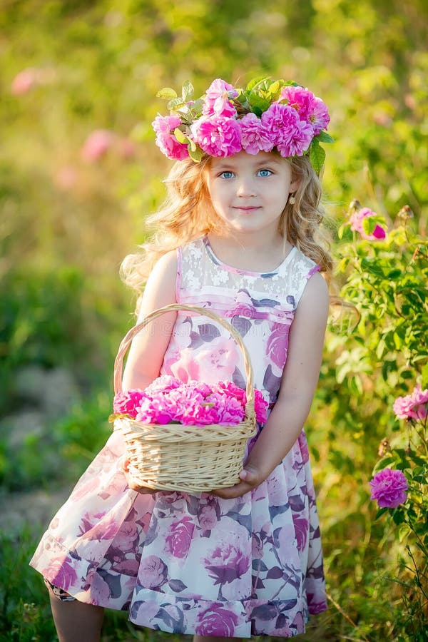Een klein meisje met mooi lang blond haar, kleedde zich in een lichte kleding en een kroon van echte bloemen op haar hoofd, in stock afbeeldingen Een klein meisje met mooi lang blond haar, kleedde zich in een lichte kleding en een kroon van echte bloemen op haar hoofd, in stock afbeeldingen