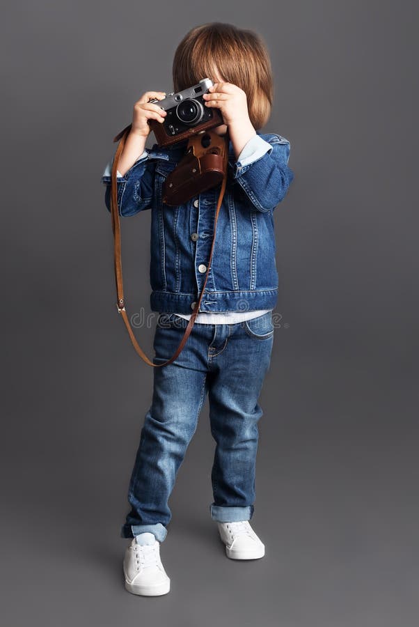 Een kleine jongen in denim probeert om een spruit te nemen gebruikend een uitstekende camera stock foto's Een kleine jongen in denim probeert om een spruit te nemen gebruikend een uitstekende camera stock foto's