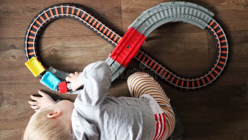 Een kleine jongen speelt een spoorweg van kinderen Het mamma let hierboven op haar zoon van Het kind wordt gefascineerd door de t stock fotografie Een kleine jongen speelt een spoorweg van kinderen Het mamma let hierboven op haar zoon van Het kind wordt gefascineerd door de t stock fotografie