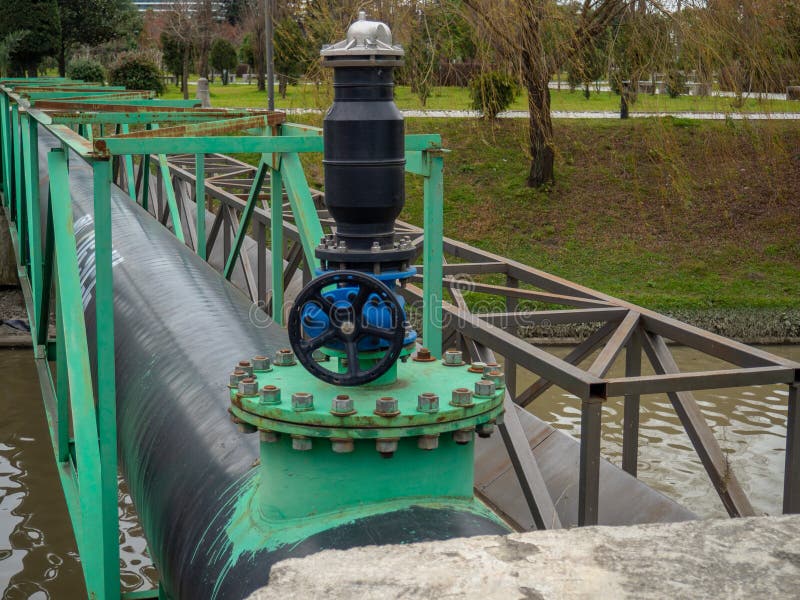 A valve on a large black pipe. Oil pipeline on the bridge. Transportation of fluid through pipes. A valve on a large black pipe. Oil pipeline on the bridge. Transportation of fluid through pipes