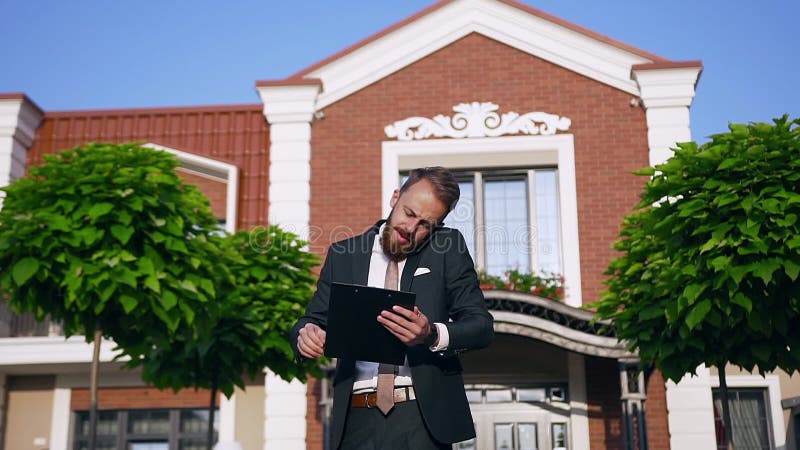 Een knappe man met baard, gekleed in de kostuum van het bedrijf en vastgebonden in de buurt van het kantoor, terwijl