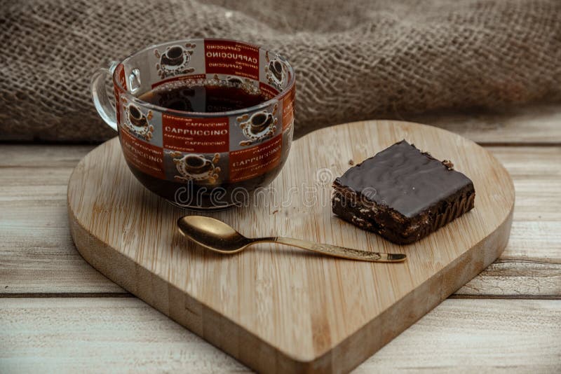 Een kop van koffie met een cake van de chocoladewafel op een houten hart-vormig dienblad royalty-vrije stock foto Een kop van koffie met een cake van de chocoladewafel op een houten hart-vormig dienblad royalty-vrije stock foto