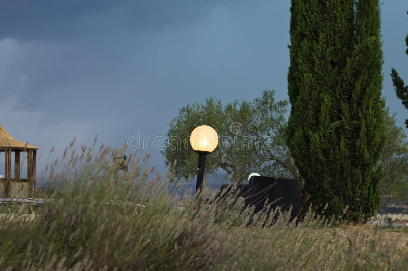 A crooked street lamp in the garden illuminated in the evening Umbria, Italy, Europe. A crooked street lamp in the garden illuminated in the evening Umbria, Italy, Europe