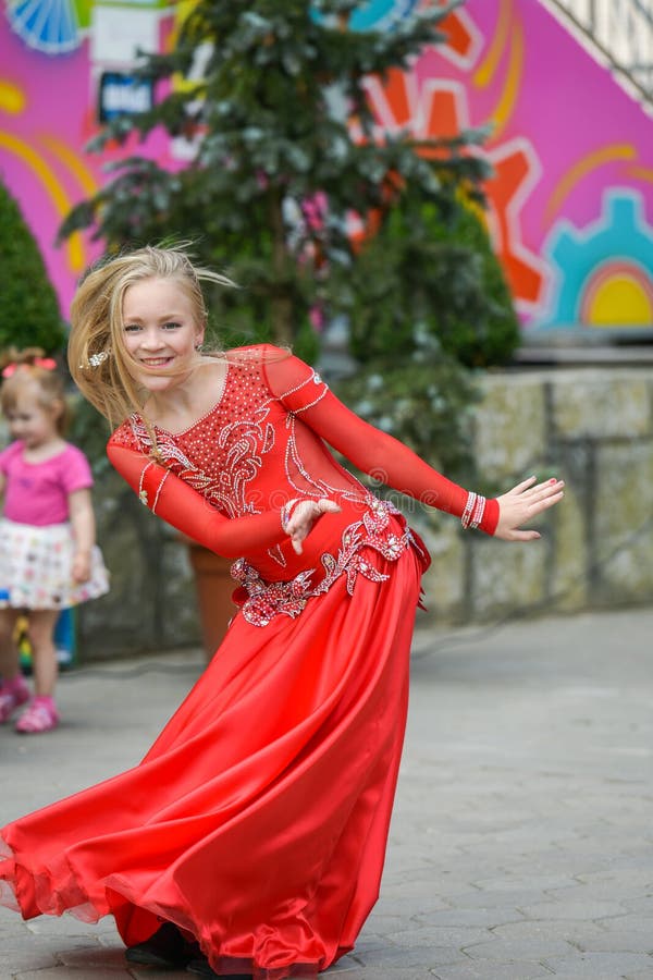 Een leuk meisje in een rood kostuum danst op de straat Meisje in de dansklasse Het babymeisje leert dans Toon dans aan stock foto Een leuk meisje in een rood kostuum danst op de straat Meisje in de dansklasse Het babymeisje leert dans Toon dans aan stock foto