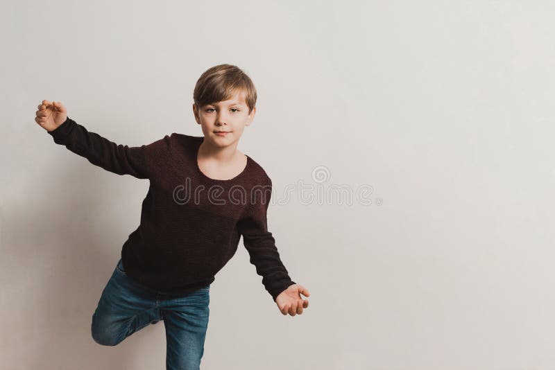 Een leuke jongen door de witte muur, bruine trui, jeans royalty-vrije stock afbeeldingen Een leuke jongen door de witte muur, bruine trui, jeans royalty-vrije stock afbeeldingen