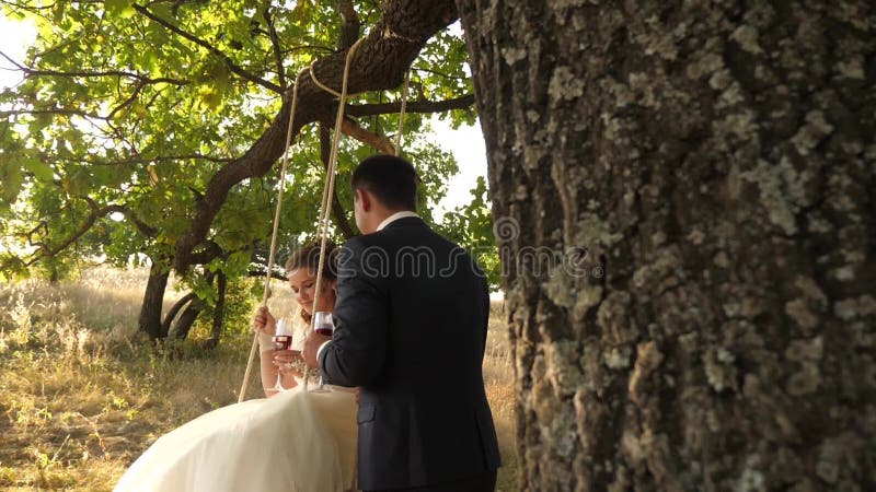 Een liefdevol stel op een zwaai in het park zwaaien op een touw op een boomtak vrolijke huwelijksreis