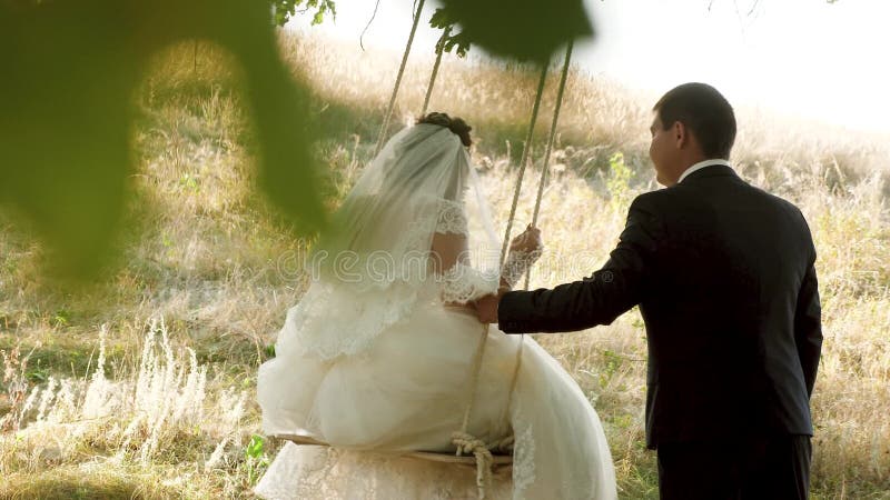 Een liefdevol stel op een zwaai in het park zwaaien op een touw op een boomtak vrolijke huwelijksreis