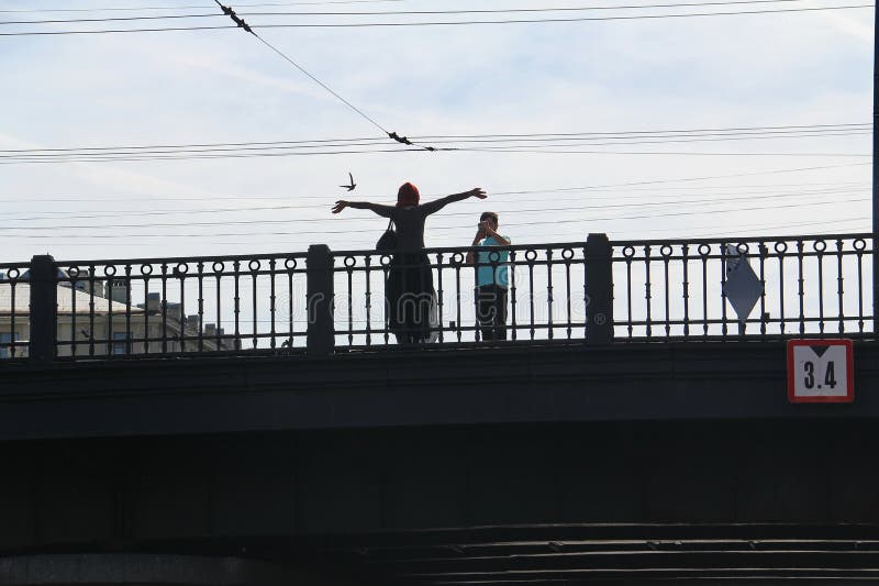Een man op de brug fotografeert op de telefoon een jonge vrouw royalty-vrije stock foto's Een man op de brug fotografeert op de telefoon een jonge vrouw royalty-vrije stock foto's