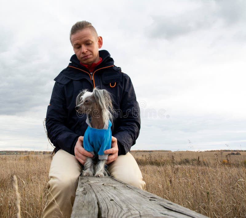 Een man van middelbare leeftijd loopt met een hondenras Chinees Hairless Crested Dog op de natuur in de herfstnamiddag royalty-vrije stock foto Een man van middelbare leeftijd loopt met een hondenras Chinees Hairless Crested Dog op de natuur in de herfstnamiddag royalty-vrije stock foto
