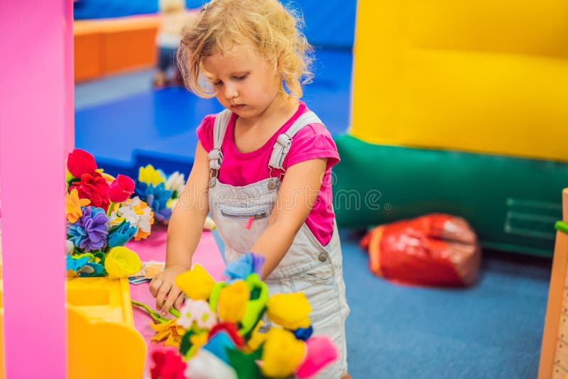 Een meisje speelt in een bloemwinkel, kiest bloemen royalty-vrije stock afbeelding Een meisje speelt in een bloemwinkel, kiest bloemen royalty-vrije stock afbeelding