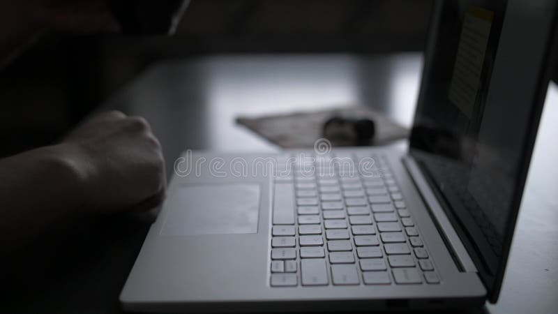 Een mens bij de lijst werkt in de avond aan laptop door het venster en drinkt koffieclose-up