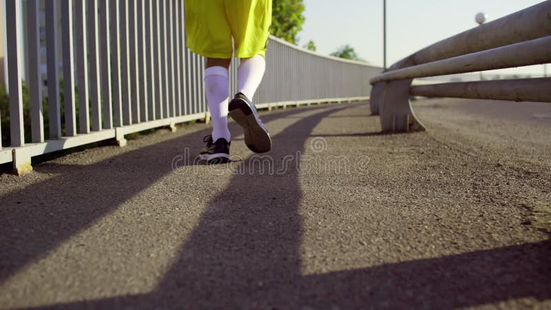Een mens in de looppas van sportenkleren over de brug in de ochtend