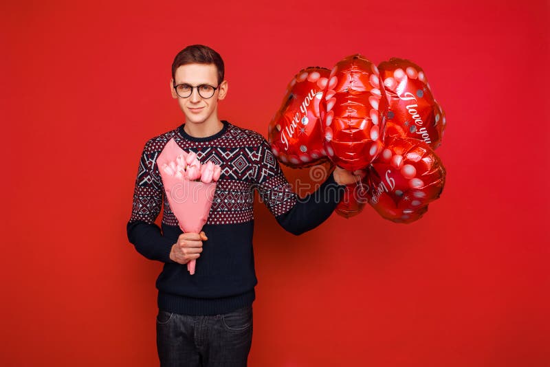 Een mens die glazen met een bos van bloemen en hart-vormige ballons op een rode achtergrond dragen De dag van de valentijnskaart stock afbeeldingen Een mens die glazen met een bos van bloemen en hart-vormige ballons op een rode achtergrond dragen De dag van de valentijnskaart stock afbeeldingen