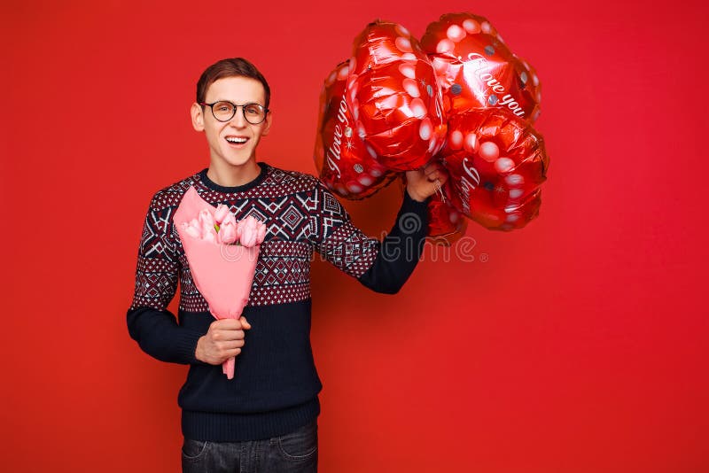 Een mens die glazen met een bos van bloemen en hart-vormige ballons op een rode achtergrond dragen De dag van de valentijnskaart royalty-vrije stock fotografie Een mens die glazen met een bos van bloemen en hart-vormige ballons op een rode achtergrond dragen De dag van de valentijnskaart royalty-vrije stock fotografie