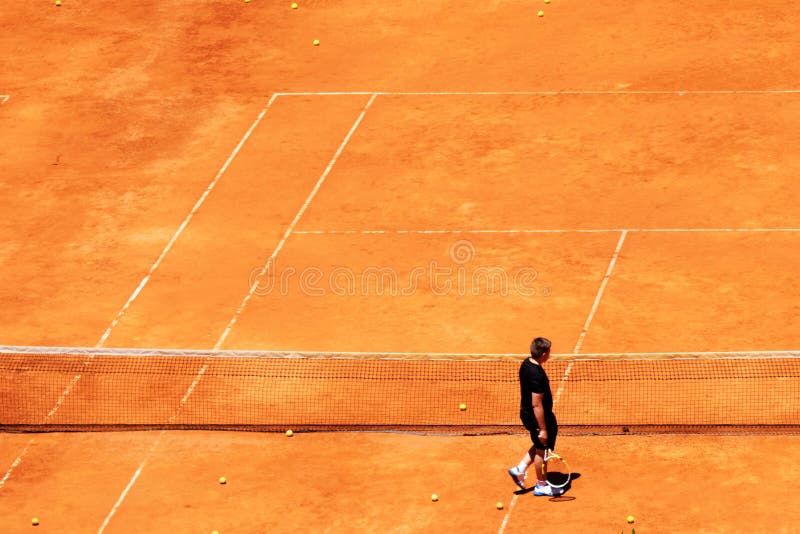 Een mens die in een tennis rode gele bal lopen op een kleitennisbaan stock foto Een mens die in een tennis rode gele bal lopen op een kleitennisbaan stock foto