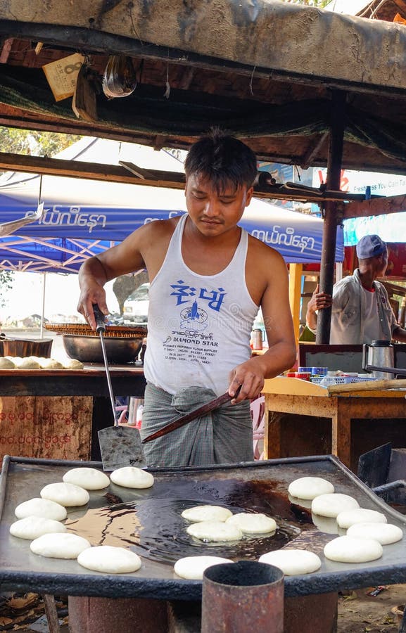 Een mens die traditionele cakes koken bij de markt in Bagan, Myanmar stock foto Een mens die traditionele cakes koken bij de markt in Bagan, Myanmar stock foto