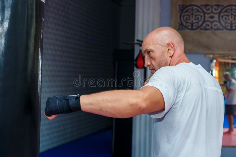 Een mens leidt bij de MMA-zak op om de builen uit te werken royalty-vrije stock foto Een mens leidt bij de MMA-zak op om de builen uit te werken royalty-vrije stock foto