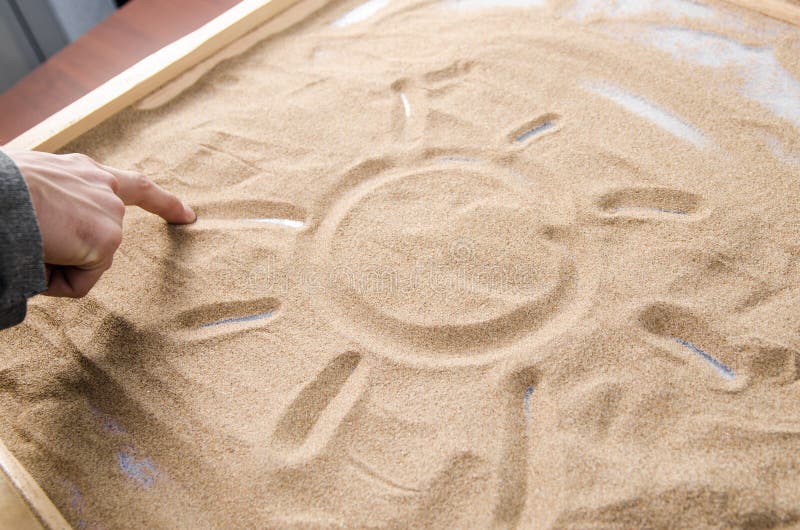 Een mens trekt op het zandsymbool van de zon royalty-vrije stock afbeeldingen Een mens trekt op het zandsymbool van de zon royalty-vrije stock afbeeldingen
