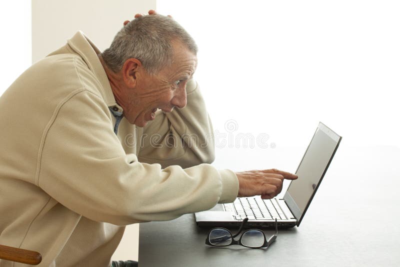 Een mens zit zeer verrast het kijken met open mond aangezien hij aan het scherm van een notitieboekjecomputer richt Hij leest of stock foto's Een mens zit zeer verrast het kijken met open mond aangezien hij aan het scherm van een notitieboekjecomputer richt Hij leest of stock foto's