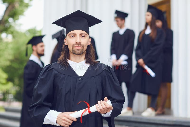 Een mensengediplomeerde glimlacht tegen de achtergrond van mensen met universitaire diploma's royalty-vrije stock foto's Een mensengediplomeerde glimlacht tegen de achtergrond van mensen met universitaire diploma's royalty-vrije stock foto's