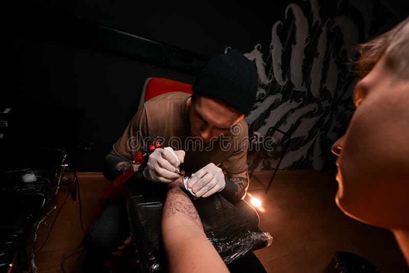 Een mensenmeester vult een tatoegering aan een jonge mens Tatoegeringswoonkamer Het trekken op huid royalty-vrije stock fotografie Een mensenmeester vult een tatoegering aan een jonge mens Tatoegeringswoonkamer Het trekken op huid royalty-vrije stock fotografie