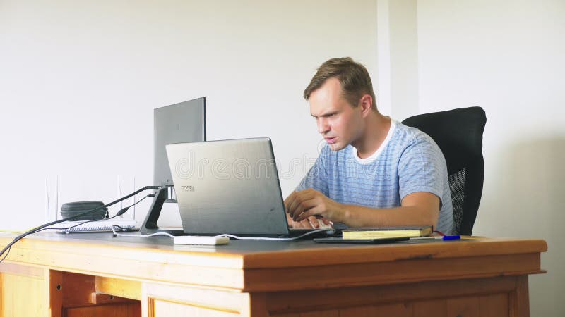 Een mensenzitting bij een bureau thuis, thuis werkend computer en laptop