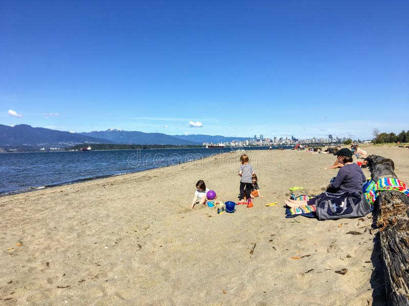 Een moeder en drie kinderen bij strand het spelen in het zand op een mooie zonnige dag langs Spaanse Banken royalty-vrije stock foto Een moeder en drie kinderen bij strand het spelen in het zand op een mooie zonnige dag langs Spaanse Banken royalty-vrije stock foto