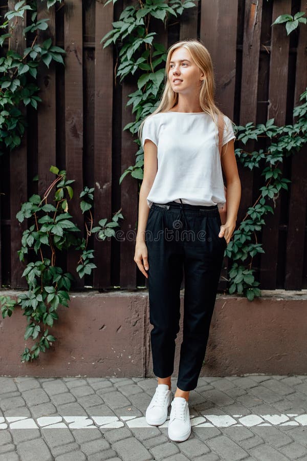 Een mooi meisje kleedde zich in openlucht in een witte t-shirttribunes, aga stock foto Een mooi meisje kleedde zich in openlucht in een witte t-shirttribunes, aga stock foto