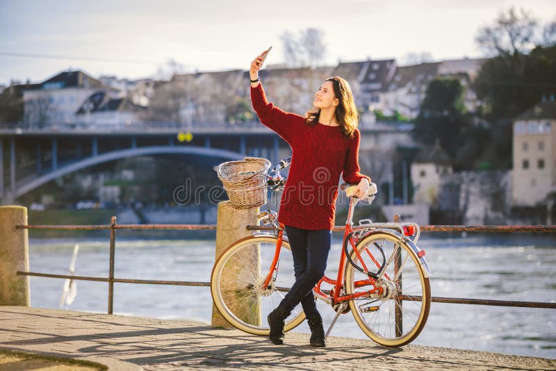Een mooie jonge vrouw met een retro rode fiets maakt een foto van zich in de oude stad van Europa op de Rivier Rijn embankm stock foto's Een mooie jonge vrouw met een retro rode fiets maakt een foto van zich in de oude stad van Europa op de Rivier Rijn embankm stock foto's