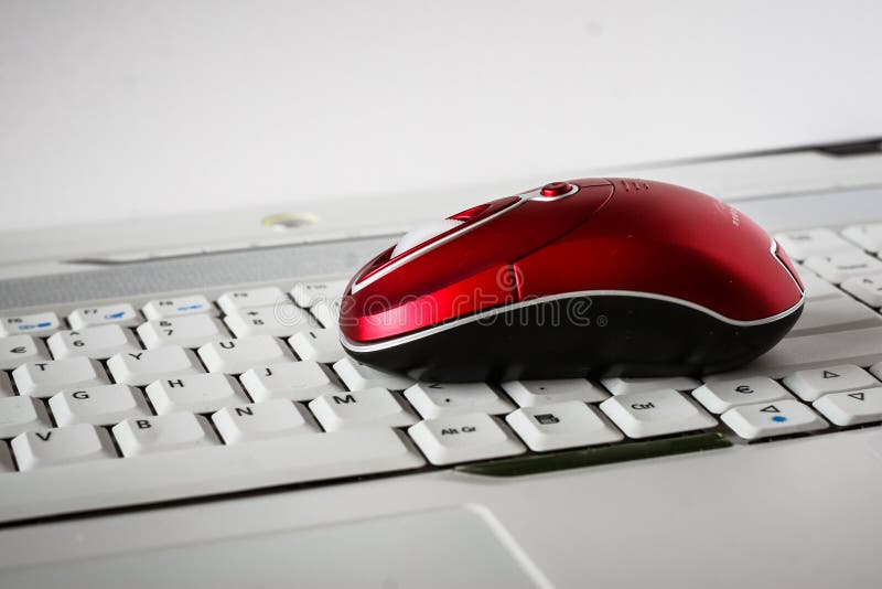 A beautiful red wireless mouse on the white keyboard of a laptop. Shallow depth of field. A beautiful red wireless mouse on the white keyboard of a laptop. Shallow depth of field