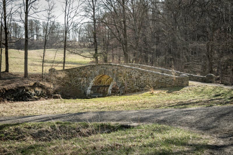Een oude steenbrug die over een kleine kreek in het bos leiden stock foto's Een oude steenbrug die over een kleine kreek in het bos leiden stock foto's