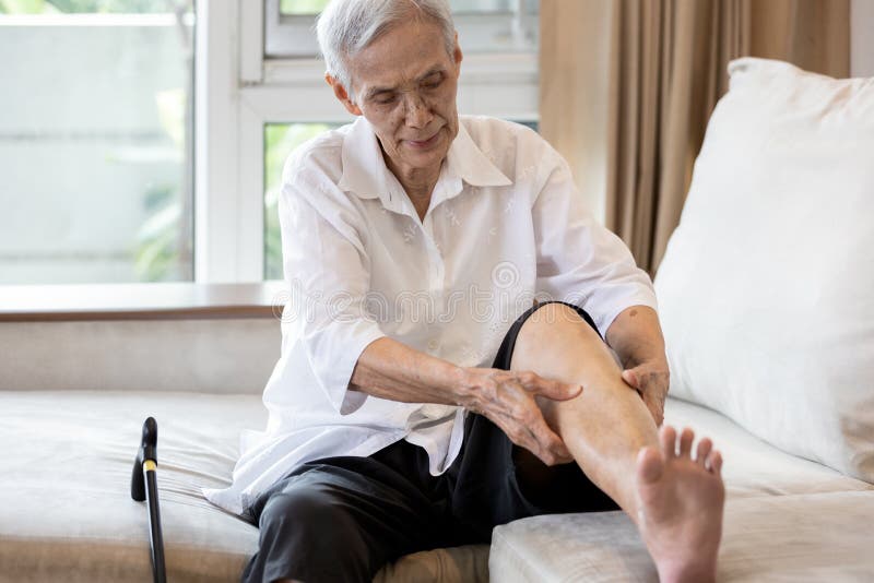 Een oudere aziatische vrouw houdt haar been vast die pijn heeft in de benen bejaarde patiënt heeft krampen in haar kalveren die he