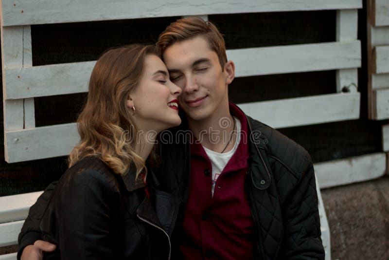 Een paar in liefde zit het omhelzen, met gesloten ogen en het glimlachen de de herfstdatum luistert aan stiltelied van liefde stock foto Een paar in liefde zit het omhelzen, met gesloten ogen en het glimlachen de de herfstdatum luistert aan stiltelied van liefde stock foto