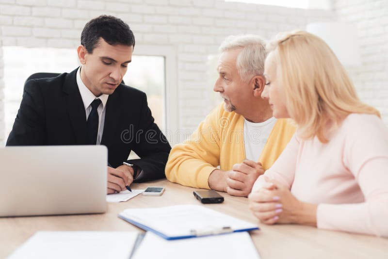 A couple of old people came to a consultation with a lawyer. The lawyer communicates with a men and a woman. They are in the lawyer`s office. In front of them is a laptop and blank forms. A couple of old people came to a consultation with a lawyer. The lawyer communicates with a men and a woman. They are in the lawyer`s office. In front of them is a laptop and blank forms.