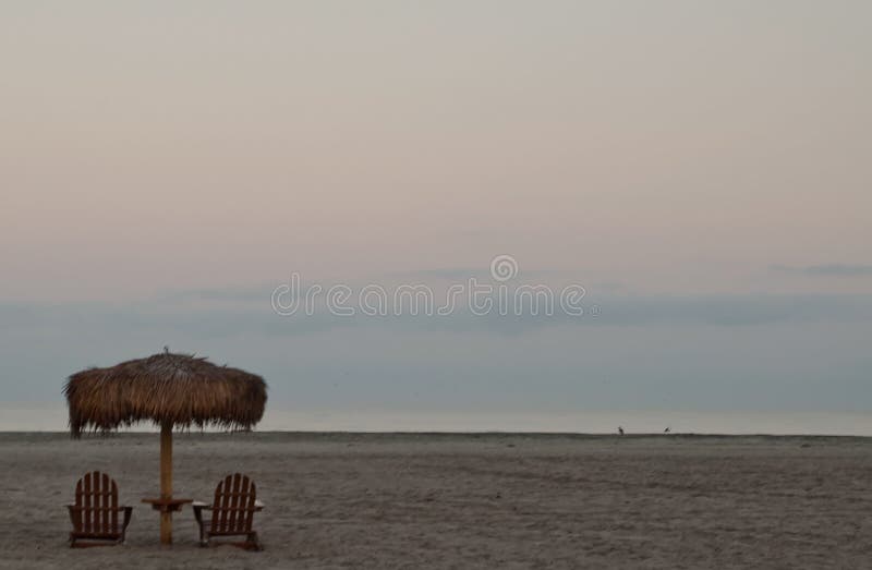Een palmparaplubak boven houten adirondackstoelen op een Vreedzaam oceaanstrand royalty-vrije stock foto Een palmparaplubak boven houten adirondackstoelen op een Vreedzaam oceaanstrand royalty-vrije stock foto