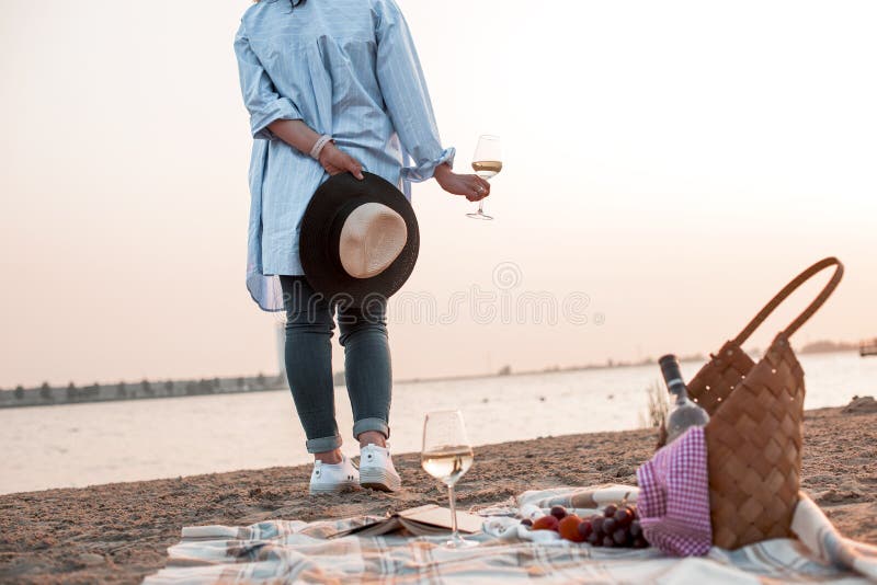 Een partij op het strand bij zonsondergang en een meisje met een glas wijn Romantische avond in de zomer door het overzees Pickni royalty-vrije stock afbeeldingen Een partij op het strand bij zonsondergang en een meisje met een glas wijn Romantische avond in de zomer door het overzees Pickni royalty-vrije stock afbeeldingen