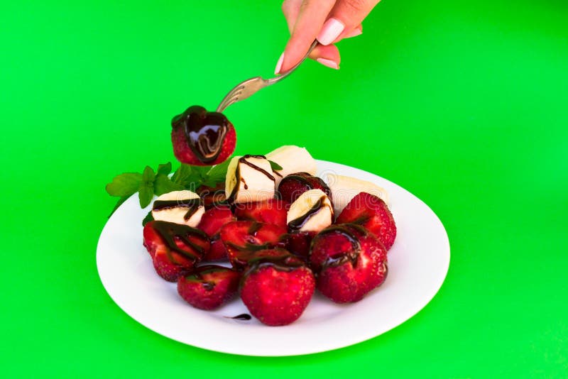 Een plaat met aardbeien en banaan en van een vrouw hand neemt aardbeien op een groene achtergrond royalty-vrije stock foto Een plaat met aardbeien en banaan en van een vrouw hand neemt aardbeien op een groene achtergrond royalty-vrije stock foto