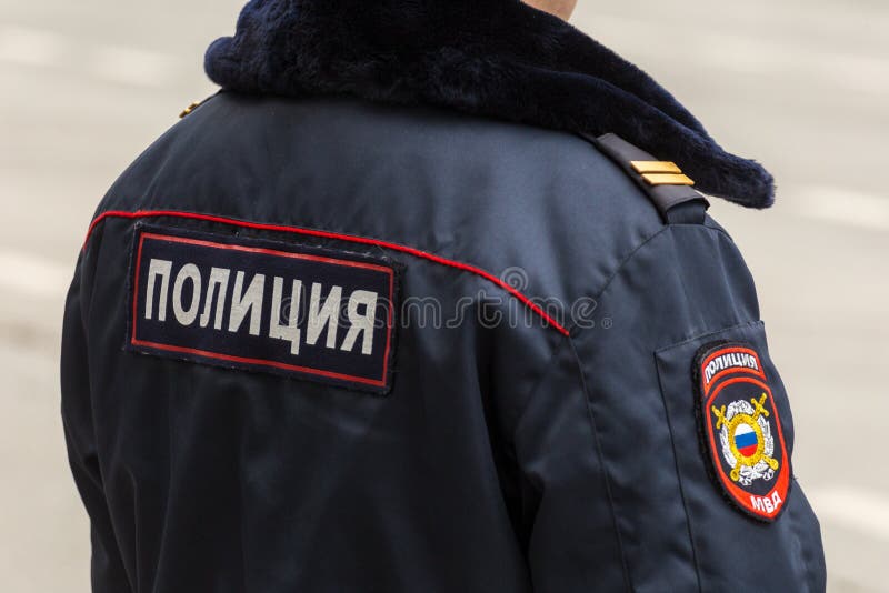Een politieagent in de winter eenvormige tribunes met zijn rug De de inschrijvings ‚politie op het jasje bij de rug royalty-vrije stock afbeelding Een politieagent in de winter eenvormige tribunes met zijn rug De de inschrijvings ‚politie op het jasje bij de rug royalty-vrije stock afbeelding