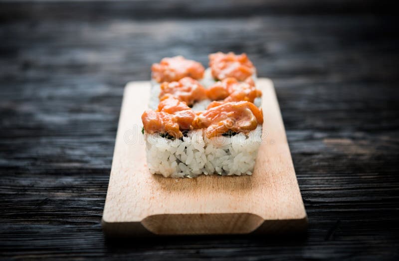 Een reeks sushi rolt met zalmbovenste laagje op houten raad stock foto's Een reeks sushi rolt met zalmbovenste laagje op houten raad stock foto's