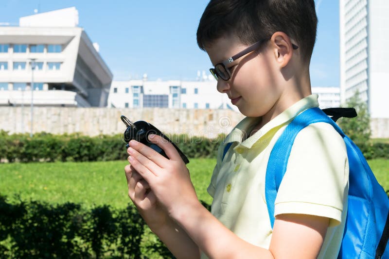Een schooljongen in het park bekijkt de wekker, die aantoont dat de tijd leert stock afbeeldingen Een schooljongen in het park bekijkt de wekker, die aantoont dat de tijd leert stock afbeeldingen