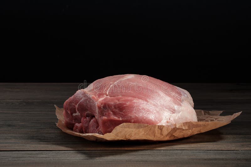 Een schouder van het stuk ruwe varkensvlees Varkensvleeshaasbiefstuk op papier op een donkere achtergrond stock fotografie Een schouder van het stuk ruwe varkensvlees Varkensvleeshaasbiefstuk op papier op een donkere achtergrond stock fotografie