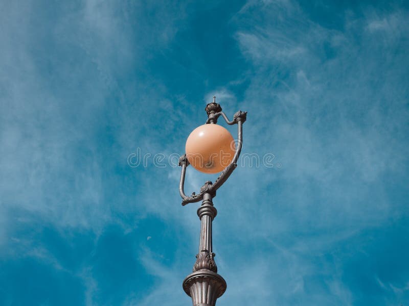 A spherical shaped vintage street lamp with metal decorations and the sky in background Gubbio, Umbria, Italy. A spherical shaped vintage street lamp with metal decorations and the sky in background Gubbio, Umbria, Italy