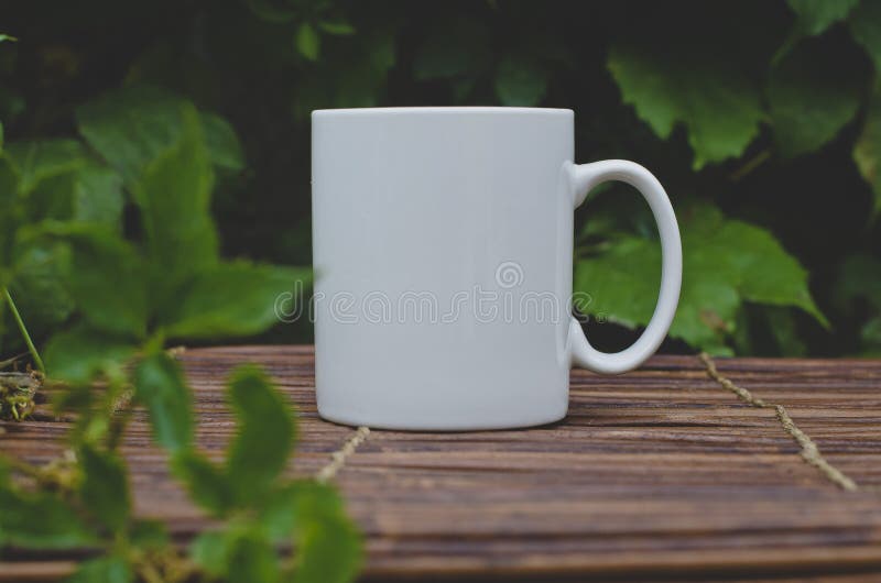 Een solo lege witte koffiemok op de houten lijst in de tuin stock afbeelding Een solo lege witte koffiemok op de houten lijst in de tuin stock afbeelding