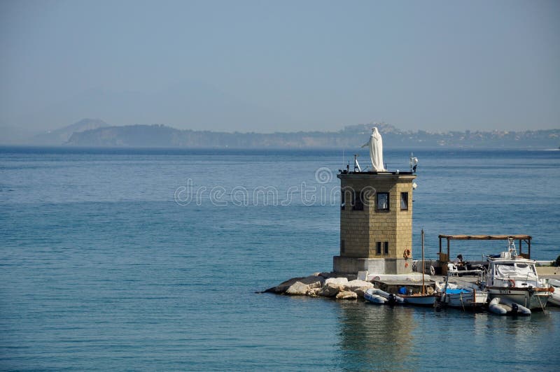 Een standbeeld in het overzees en vissersboten op het Eiland Procida, Napels/Italië stock fotografie Een standbeeld in het overzees en vissersboten op het Eiland Procida, Napels/Italië stock fotografie