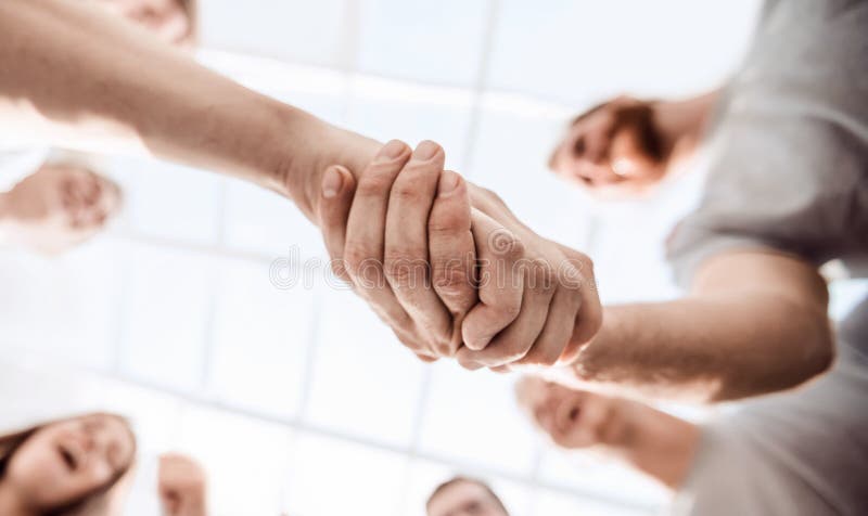 Bottom view. strong handshake of the two leaders in the circle of friends. Bottom view. strong handshake of the two leaders in the circle of friends