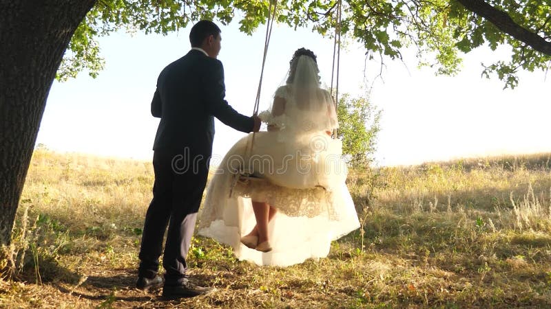 Een touw zwaaien op een boomtak vrolijke huwelijksreis liefdevol stel op een zwaai in het park