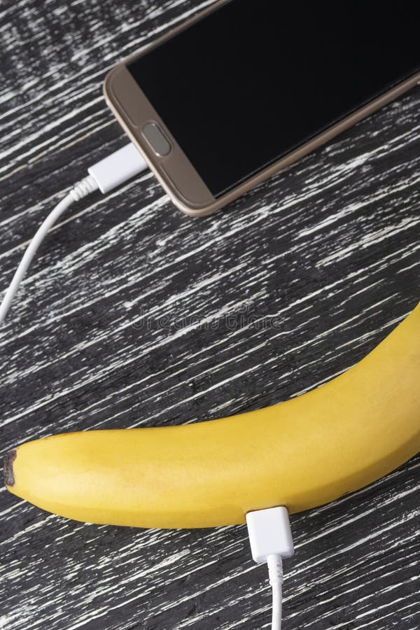 Een verse rijpe banaan wordt verbonden met de touchscreen mobiele telefoon met een witte usbkabel royalty-vrije stock foto's Een verse rijpe banaan wordt verbonden met de touchscreen mobiele telefoon met een witte usbkabel royalty-vrije stock foto's