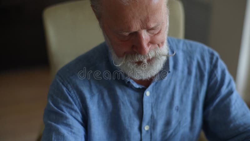 Een volwassen man met een zieke baard die op een laptop werkt en die een hoestbeeld heeft dat geschikt is voor koude kamertemperat